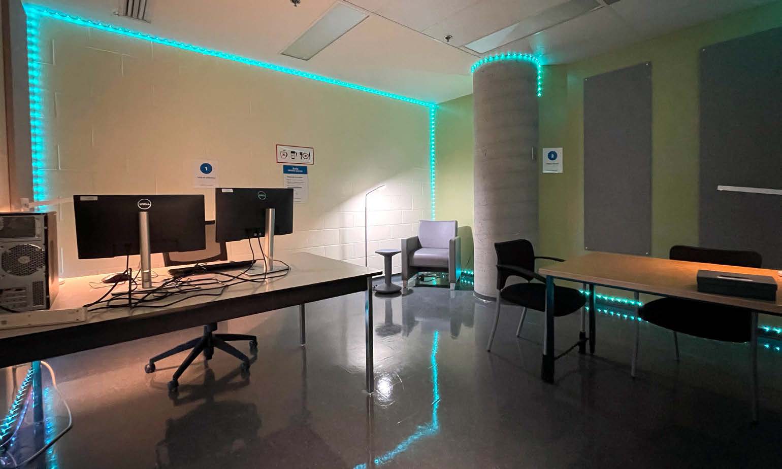 Salle adaptée à la neurodiversité avec deux espaces de travail individuels, incluant un poste informatique et un espace avec fauteuil